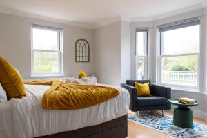 剑桥Cambridge 6-Bedroom Riverside Home with Free Parking的一间卧室,里面有一张床、一把椅子和几扇窗户。