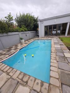 a swimming pool with blue water in front of a house at Cjabaledi Guesthouse in Centurion