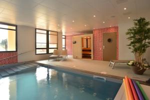 a swimming pool in a building with a pool at Domitys Le Côteau d'Argent in Saint-Doulchard