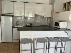 a kitchen with white cabinets and a counter with stools at Cute Apartment 150m to the beach at quite area in Denia +1 photo