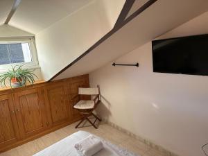 a attic room with a tv and a chair at Vallespin Suite II in Ávila
