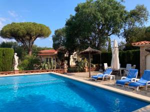 una piscina con sedie e ombrelloni accanto a una casa di Club Villamar - Casa Siete a Llagostera