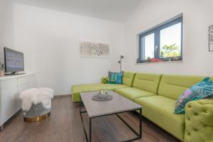 a living room with a green couch and a table at Villa Shanti, a luxurious and modern Villa surrounded by nature in Santalezi