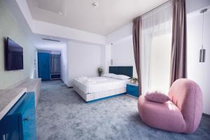 a bedroom with a bed and a pink chair at Hotel Alexandra in Mamaia