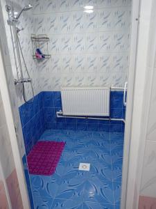 a blue tiled shower with a red mat in a bathroom at Hotel Murodjon in Samarkand