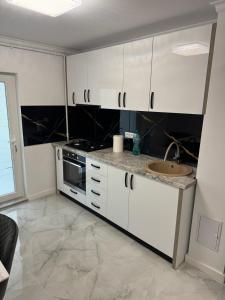 a kitchen with white cabinets and a sink at Magic Apartment in Buzau