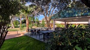 a patio with tables and chairs in a garden at Kyriad Cannes - Mandelieu in Cannes