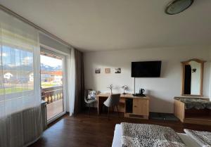 a hotel room with a bed and a desk and a window at Gästehaus-Pension Keiss in Hopferau