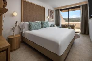 a bedroom with a large white bed and a window at Cala San Miguel Ibiza Resort, Adults only, Curio Collection by Hilton in Puerto de San Miguel