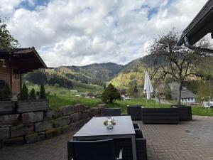 une table et des chaises sur une terrasse avec des montagnes en arrière-plan dans l'établissement Historisches Schwarzwaldhaus, à Todtnau