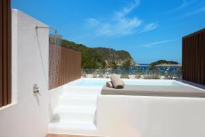 a patio with a bed and a view of the ocean at Cala San Miguel Ibiza Resort, Adults only, Curio Collection by Hilton in Puerto de San Miguel