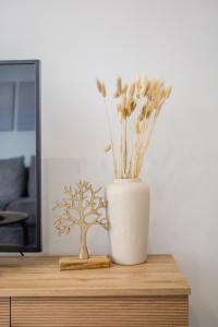 a white vase with flowers on a wooden table at H&O Sea Breeze Boutique in Chlorakas