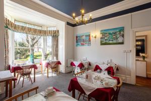 a restaurant with tables and chairs and a large window at Dunedin Guest House in Penzance