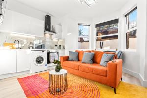 a living room with an orange couch and a kitchen at Stunning 4 Bed, Sleeps 10, Parking in London