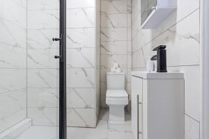 a white bathroom with a toilet and a sink at Stunning 4 Bed, Sleeps 10, Parking in London +24 photos