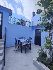 a table and chairs on a patio with a blue wall at Cozy Family House in City-Center in Chefchaouene