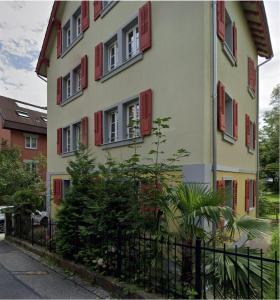 um edifício com janelas com venezianas vermelhas e uma cerca em Charming apartment central in Lucerne em Lucerna