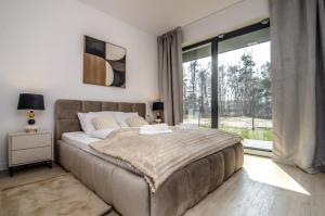 a bedroom with a large bed and a large window at Na mierzei 14 - Miedzy dwoma wodami in Mielno