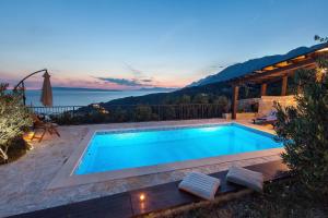 a swimming pool with a view of the ocean at Villa Oliva in Podgora
