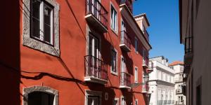 ein rotes Gebäude mit Fenstern und Balkonen auf einer Straße in der Unterkunft Lisbon Serviced Apartments - Bairro Alto in Lissabon