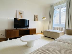 Habitación blanca con TV y cama en Le RUTHENE, en Rodez