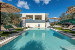 una piscina frente a una casa con sombrillas en Villa Casa Diva, en Perivólion