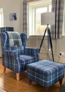 a blue chair and a ottoman in a living room at Belmont Chapel Cottage in Acharacle