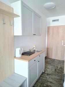 une cuisine avec des armoires blanches et un évier dans l'établissement Apartament 104 Wind w Welle, à Grzybowo 4 autres photos