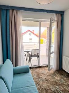- un salon avec un canapé bleu et une porte coulissante en verre dans l'établissement Apartament 104 Wind w Welle, à Grzybowo