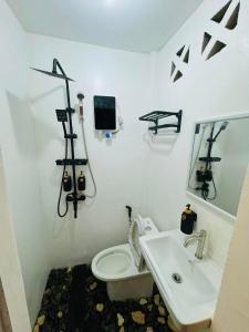 een witte badkamer met een toilet en een wastafel bij Fazzah De Siargao in General Luna +10 foto's