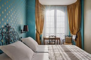 a bedroom with a bed and a window and a table at Hotel Le Grimaldi by Happyculture in Nice