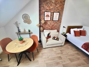 a room with a table and a bed and a chair at Les Briques Rouges, Appartement Béthune in Béthune