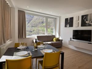 a living room with a dining room table with yellow chairs at Appartamenti TEI Orobic Experience in Premana