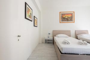 two beds in a room with white walls at Casa San Donato - M3 Station in San Donato Milanese