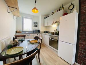 une cuisine avec une table et un réfrigérateur blanc dans l'établissement Casa Botanica, à Angers
