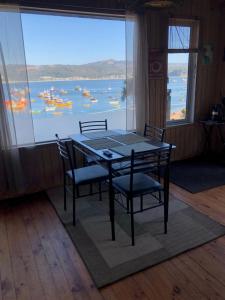 a dining room with a table and chairs and a large window at Bahía Coliumo in Tomé