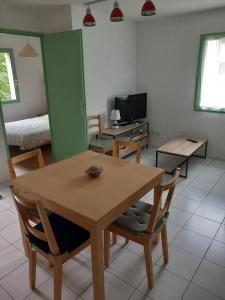 un salon avec une table et des chaises en bois dans l'établissement Bel appartement au bord du lac à Arreau, 40 m² avec piscine, à Arreau