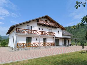 a large white house with a gambrel roof at Pensiunea Turistică La Tei in Bistricioara