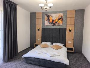 a bedroom with a bed and a painting on the wall at Pensiunea Turistică La Tei in Bistricioara