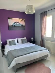 a bedroom with a large bed with a purple wall at Maison rénovée avec garage et jardin, proche centre ville - La Tremblade in La Tremblade