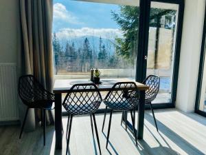 a table and chairs in a room with a large window at Daj Sobie Spokój - WIDOK 800mnpm OGRÓDEK in Szklarska Poręba