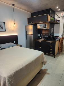 a bedroom with a bed and a kitchen with a refrigerator at Studio West Fit in Mossoró