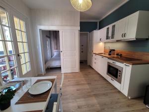 a kitchen with white cabinets and a table and a room at Graziella front de mer in Mers-les-Bains +6 photos