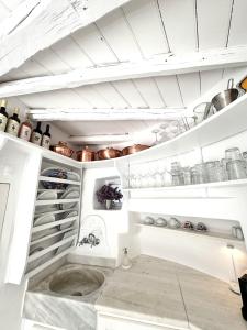 a kitchen with white cabinets and pots and pans at She Mykonos - The Iconic Windmill in Megali Ammos
