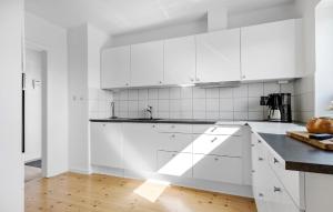 a white kitchen with white cabinets and a wooden floor at 2 Bedroom Amazing Home In Ringkøbing in Ringkøbing