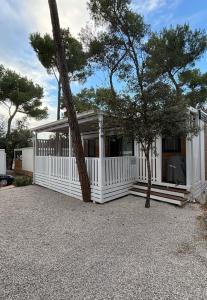 a white house with a white fence and trees at Mobile homes Eva in Biograd na Moru +20 photos
