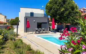 une villa avec une piscine et des parasols rouges dans l'établissement Amazing Home In Liznjan, à Ližnjan