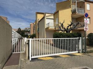 a white gate in front of a building at Appartement cosy, 2 pièces, proche plage et parking sécurisé - FR-1-229D-150 in Fleury