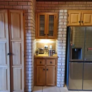 a kitchen with wooden cabinets and a refrigerator at Duckpond Lodge in Oudtshoorn +10 photos