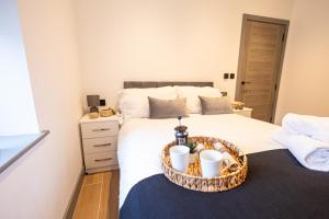 a bedroom with a bed with a tray with two cups on it at Chic 2King BD Apt London with Ensuite & Pull Out Bed in Finchley